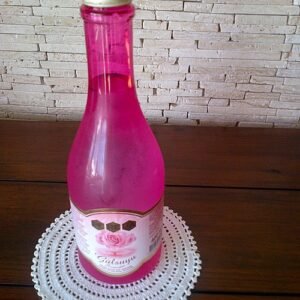 Rozenwater sprayfles met rozenblaadjes in heldere vloeistof.