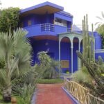 Majorelle tuin met blauwe villa en weelderige groene planten.