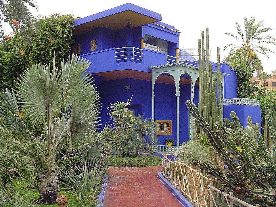 Majorelle tuin met blauwe villa en weelderige groene planten.
