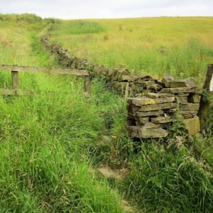 Scenic Calderdale Way hiking trail with green hills under cloudy sky.