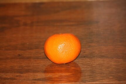 Rijpe clementine op houten tafel, met groen blad en schil.