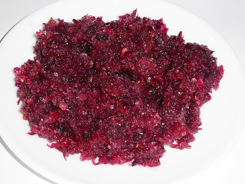 Dark pink homemade Gulkand in glass jar with fresh rose petals.