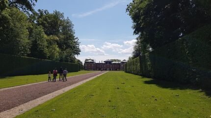 Middeleeuws kasteel met torentjes en ophaalbrug tegen groene heuvels.