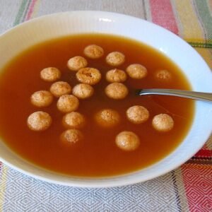 Rozenbottelsoep in een kom, rijk rood van kleur, glad van textuur.