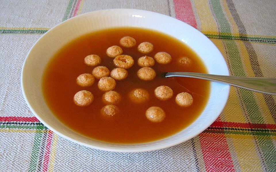 Rozenbottelsoep in een kom, rijk rood van kleur, glad van textuur.