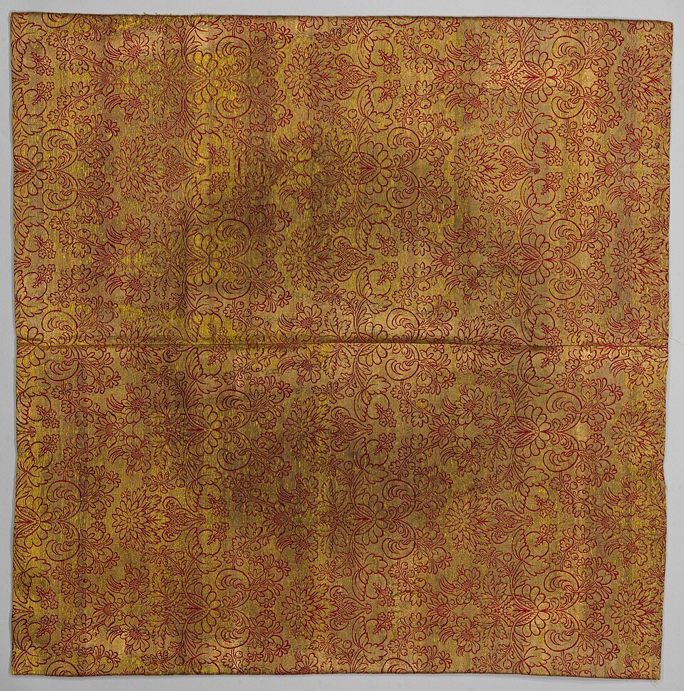 Zijden brokaat van karmijnrood op goud patroon.